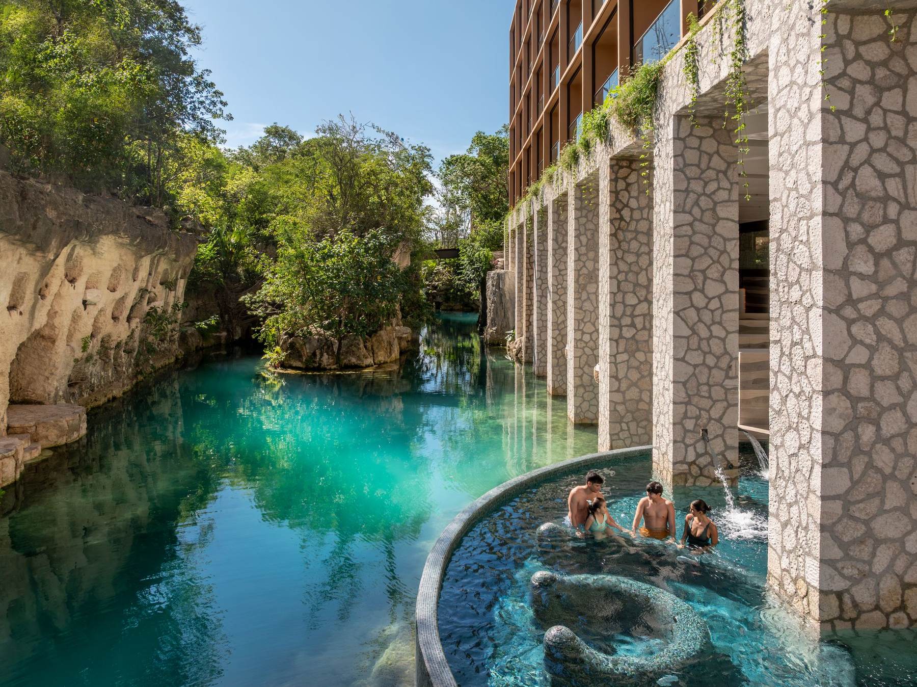 A family soaking in a turquoise pool by the spa at Hotel Xcaret México