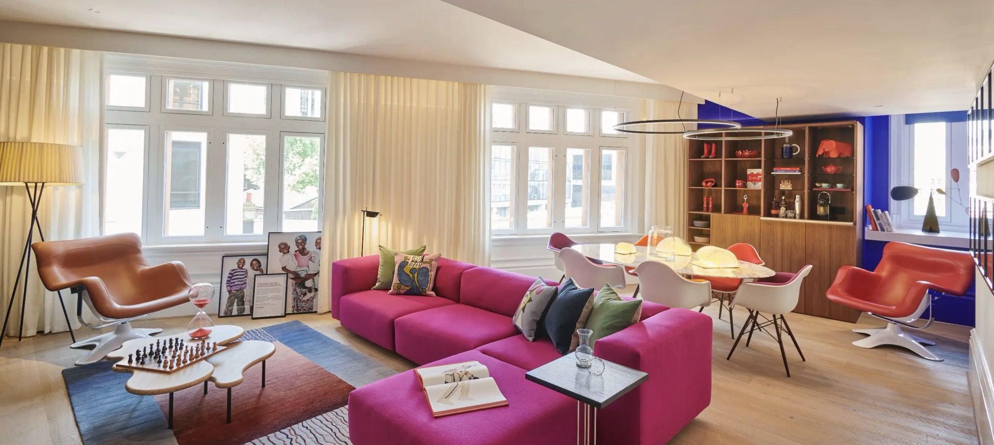 A suite living room with a pink sofa and tall windows