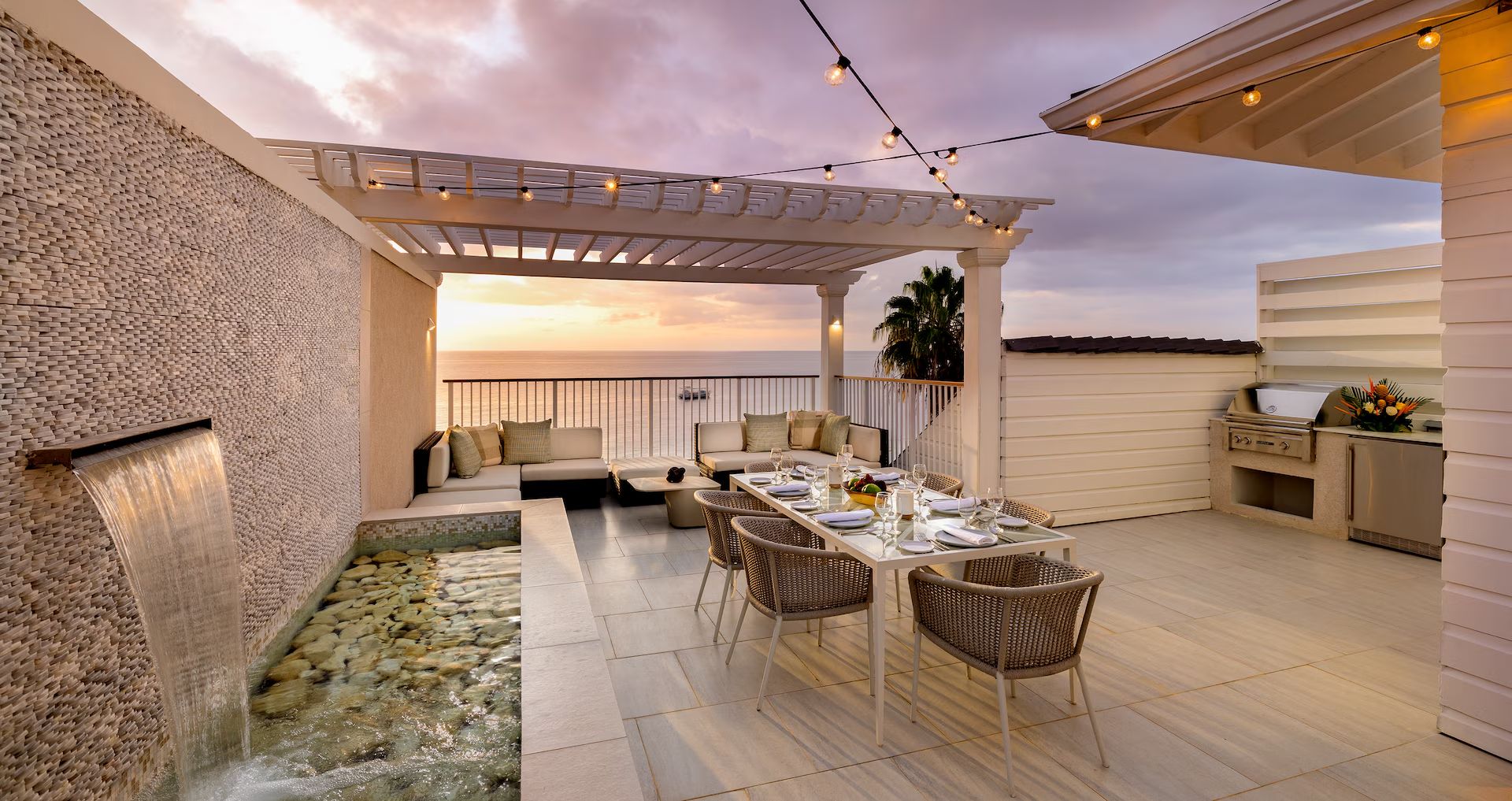 A rooftop terrace with a dining table and plunge pool at dusk
