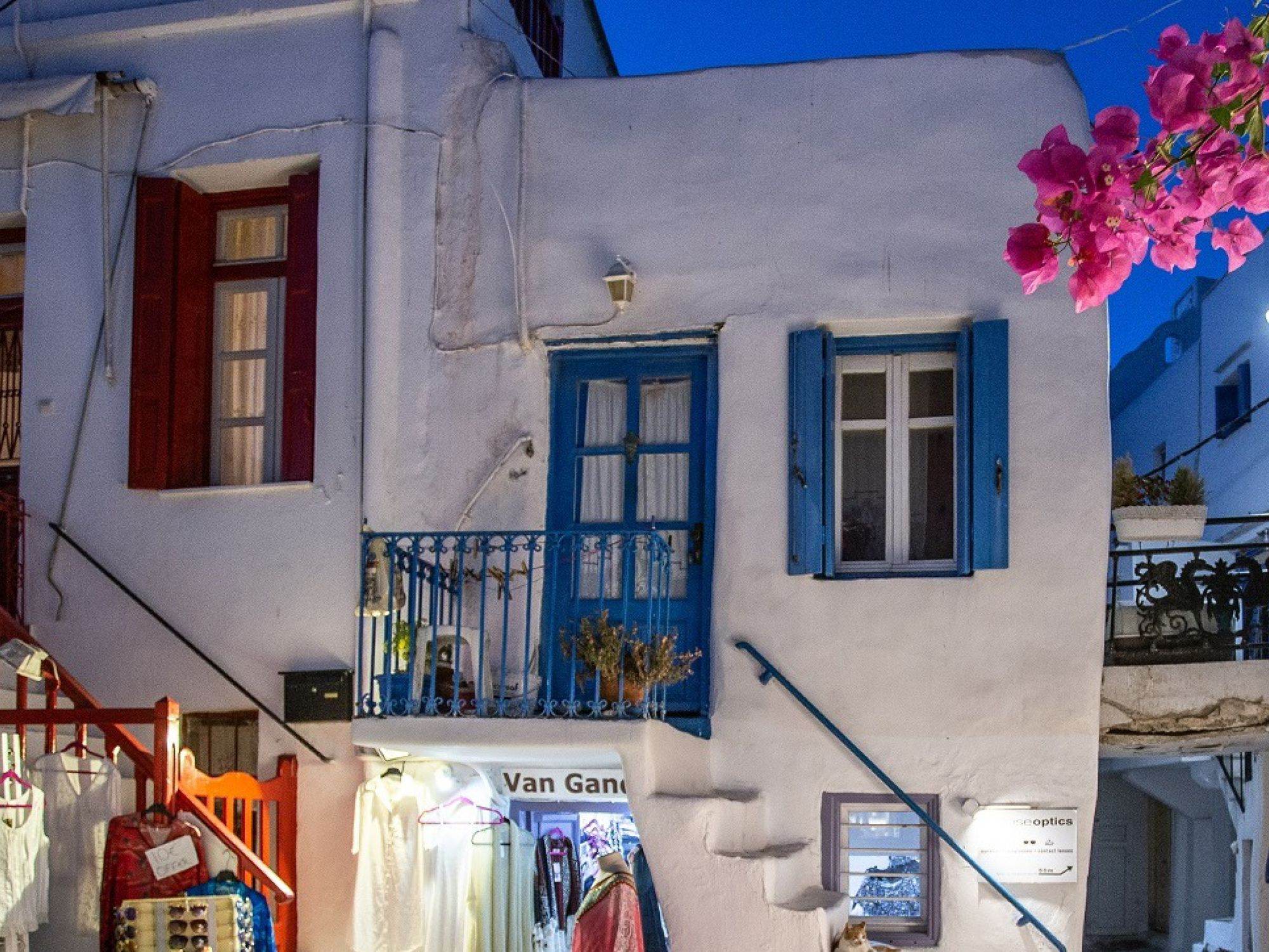A whitewashed Mykonos street with blue shutters and bougainvillea
