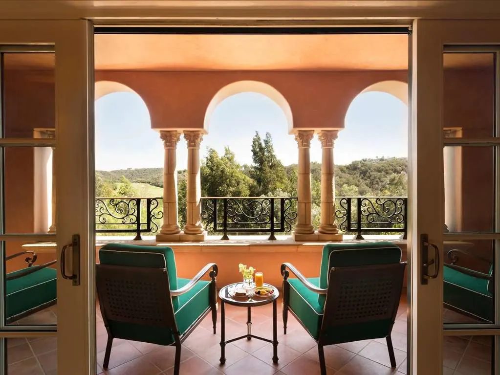 A balcony with two chairs between arched columns, looking over the canyon