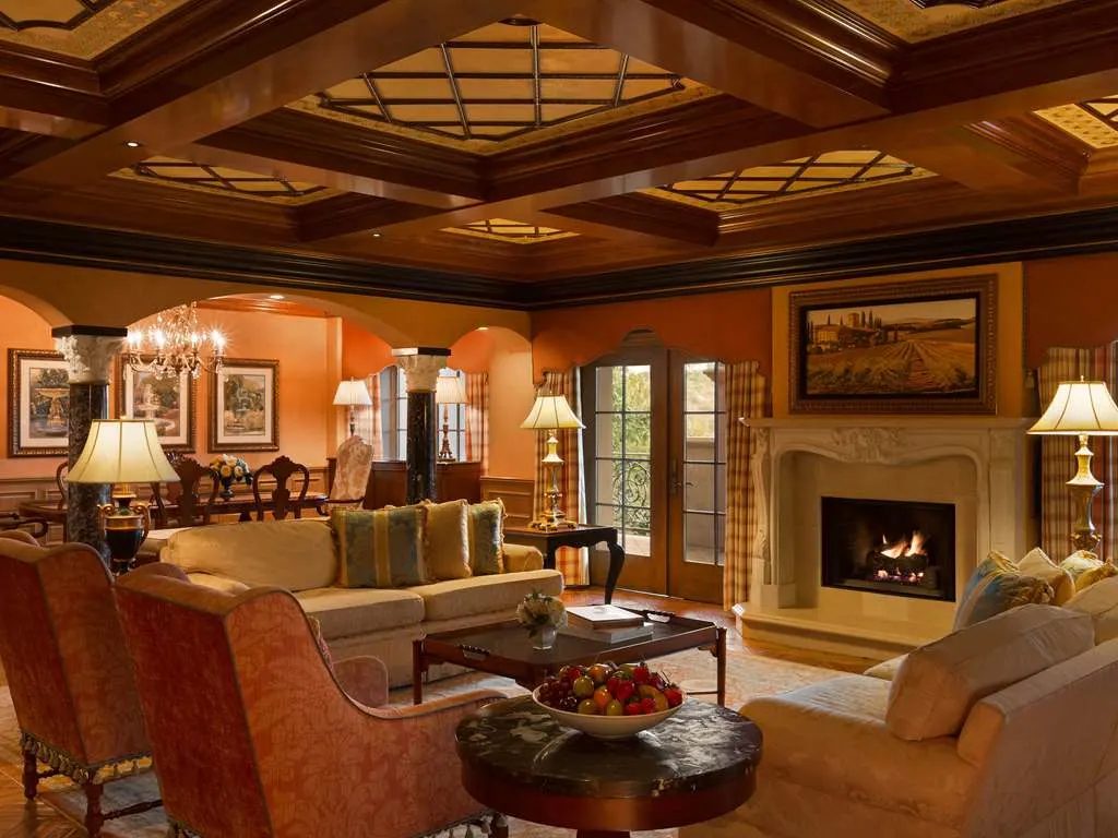 A suite living room with a fireplace beneath a coffered wood ceiling