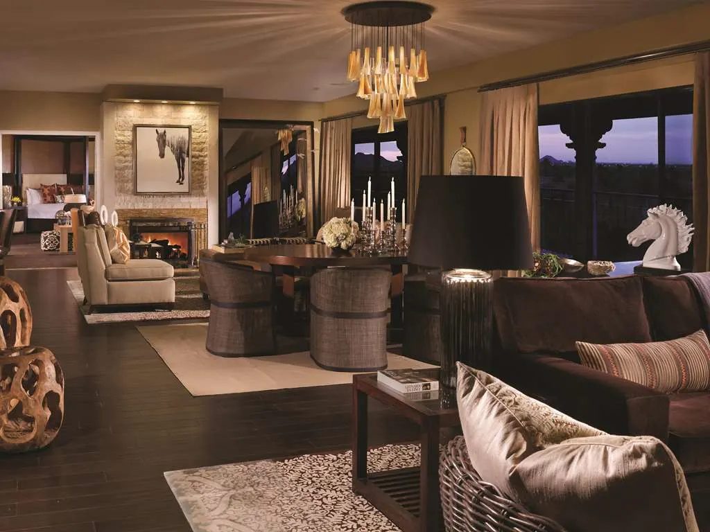 A suite living and dining room with a stone fireplace and a sculpted chandelier