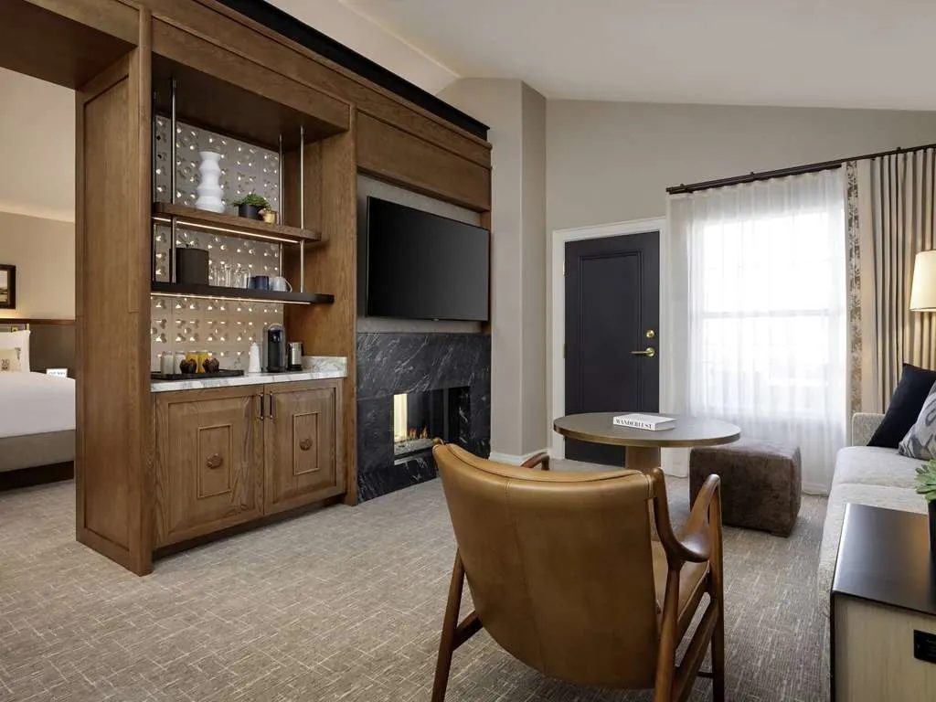 A suite with a fireplace, a wet bar, and a leather armchair