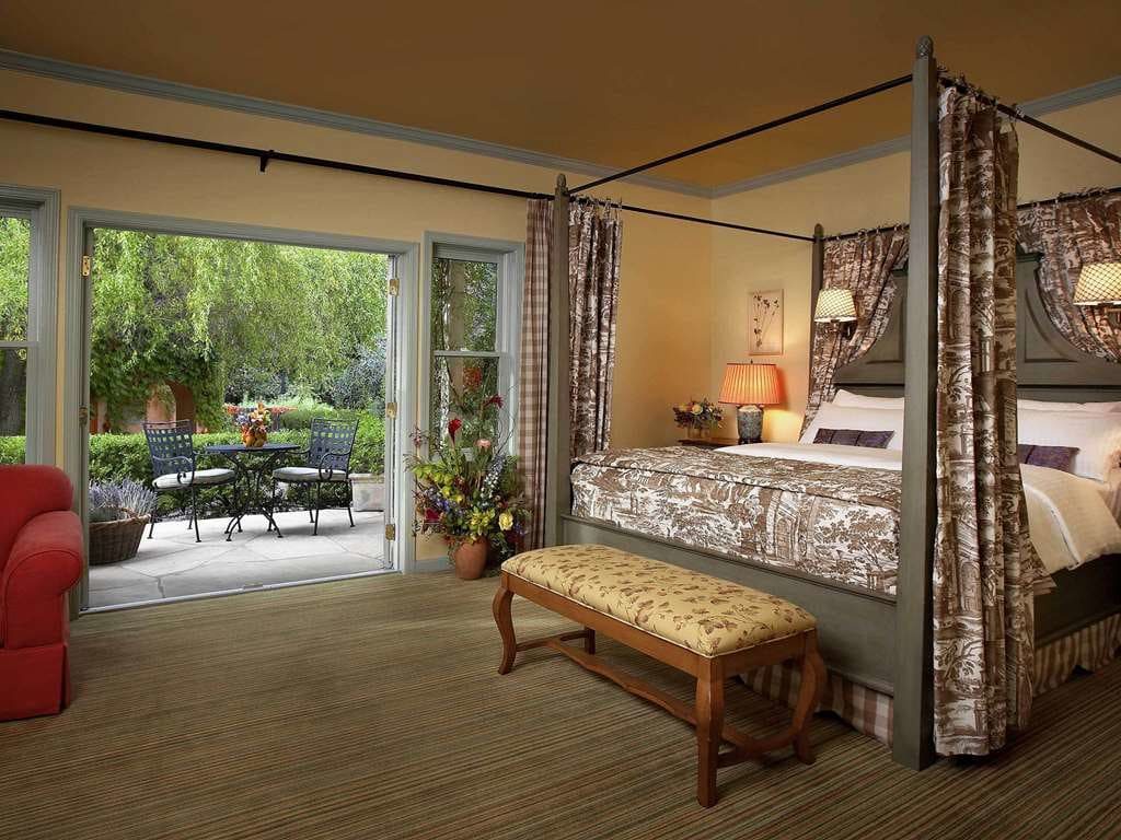 A canopy bed in a room whose French doors open onto a garden patio