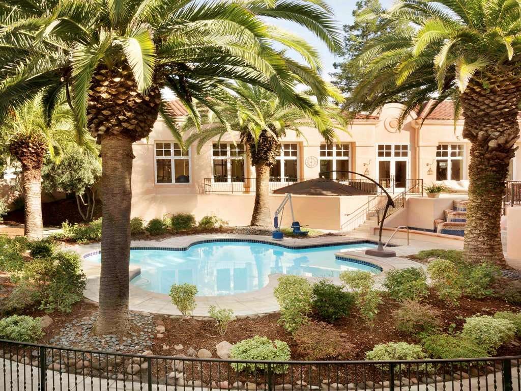 A pool among palms and gardens before the resort's pale stucco walls