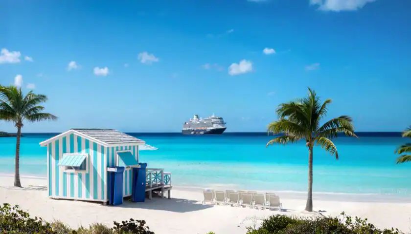 A striped beach hut and palms on Half Moon Cay, with a Holland America ship offshore