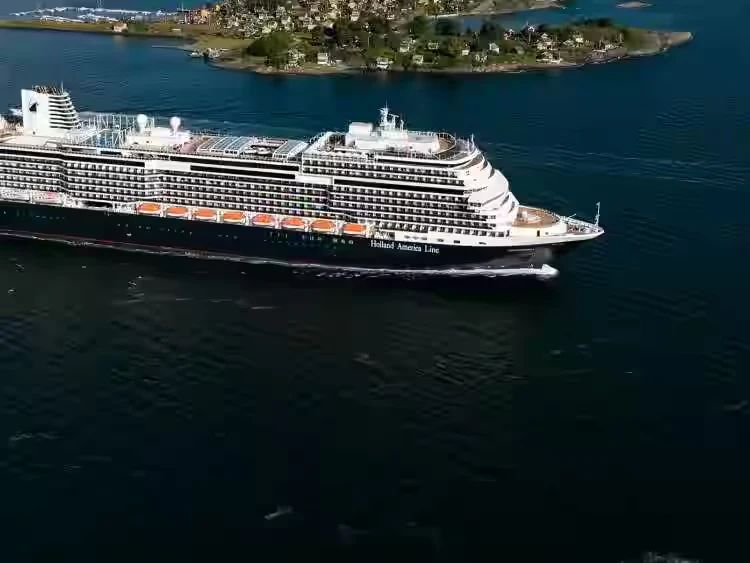 A Holland America ship sailing past rocky green islands, seen from above
