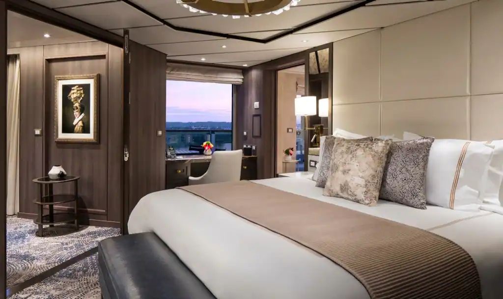 A suite bedroom with soft neutrals and a window onto the water