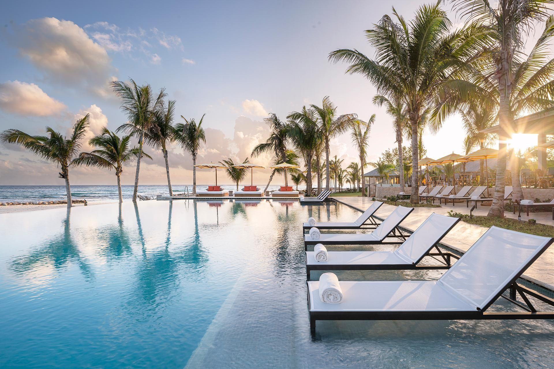 The Eclipse infinity pool at sunrise, lined with loungers and palms