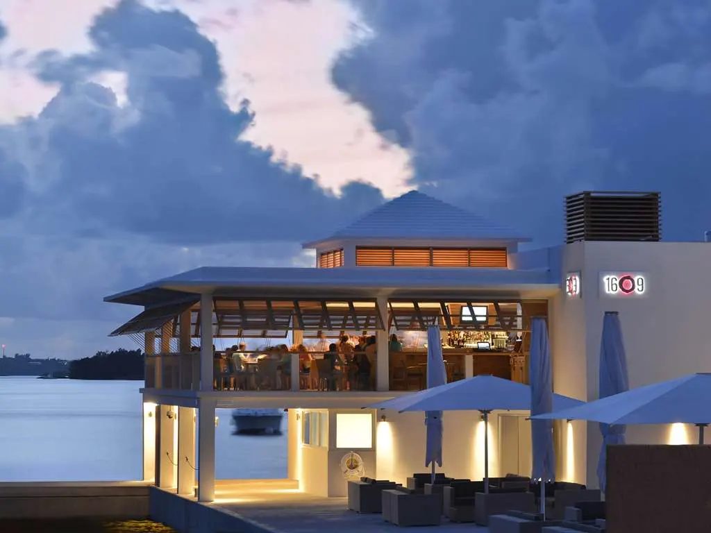 1609, the waterfront restaurant, lit at dusk beneath a stormy sky