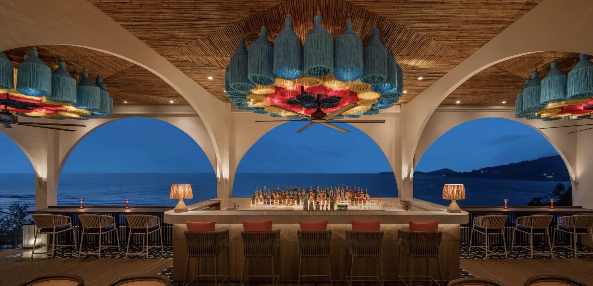 Casa Boho's bar beneath colorful lanterns, with arched views of the bay