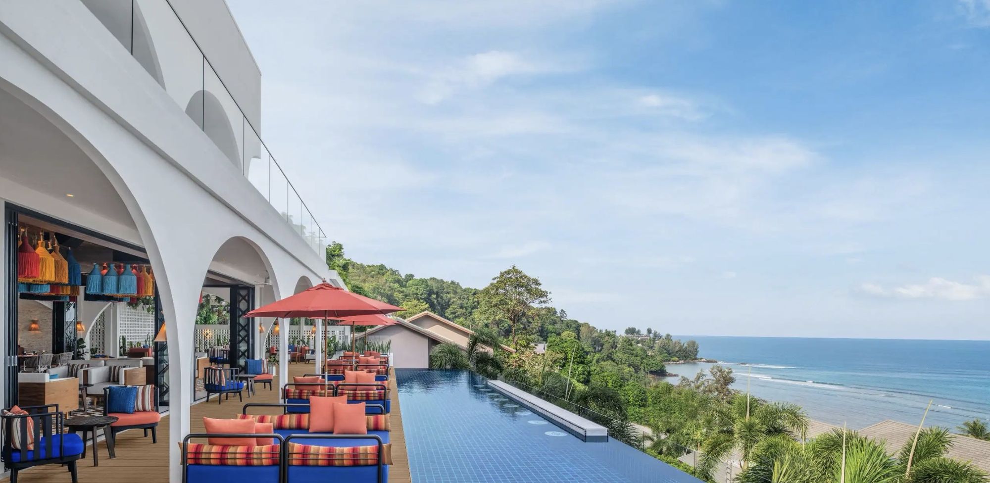 An infinity pool edged by white arches, looking down the coast