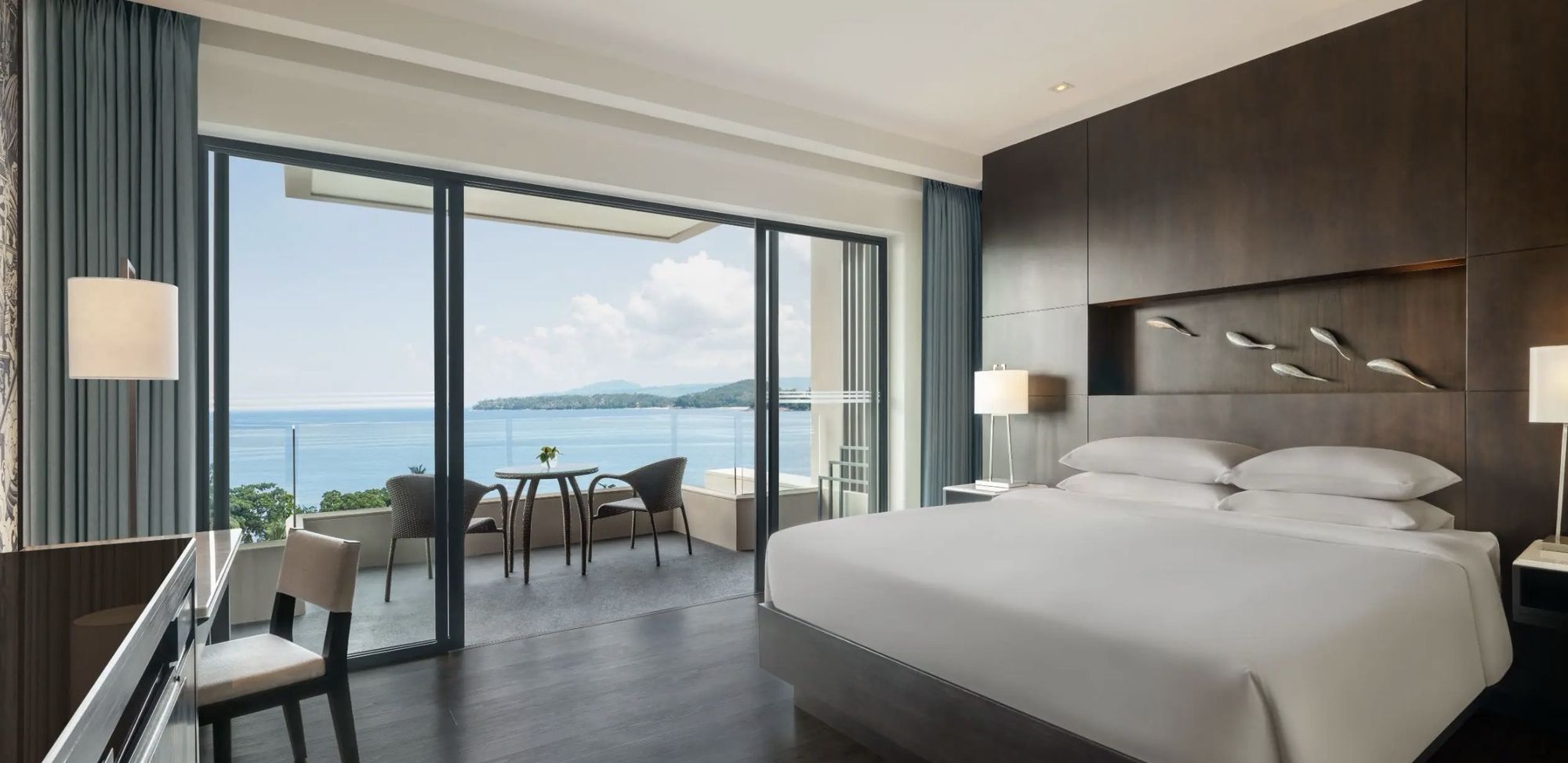 A guest room with a wide window onto the ocean