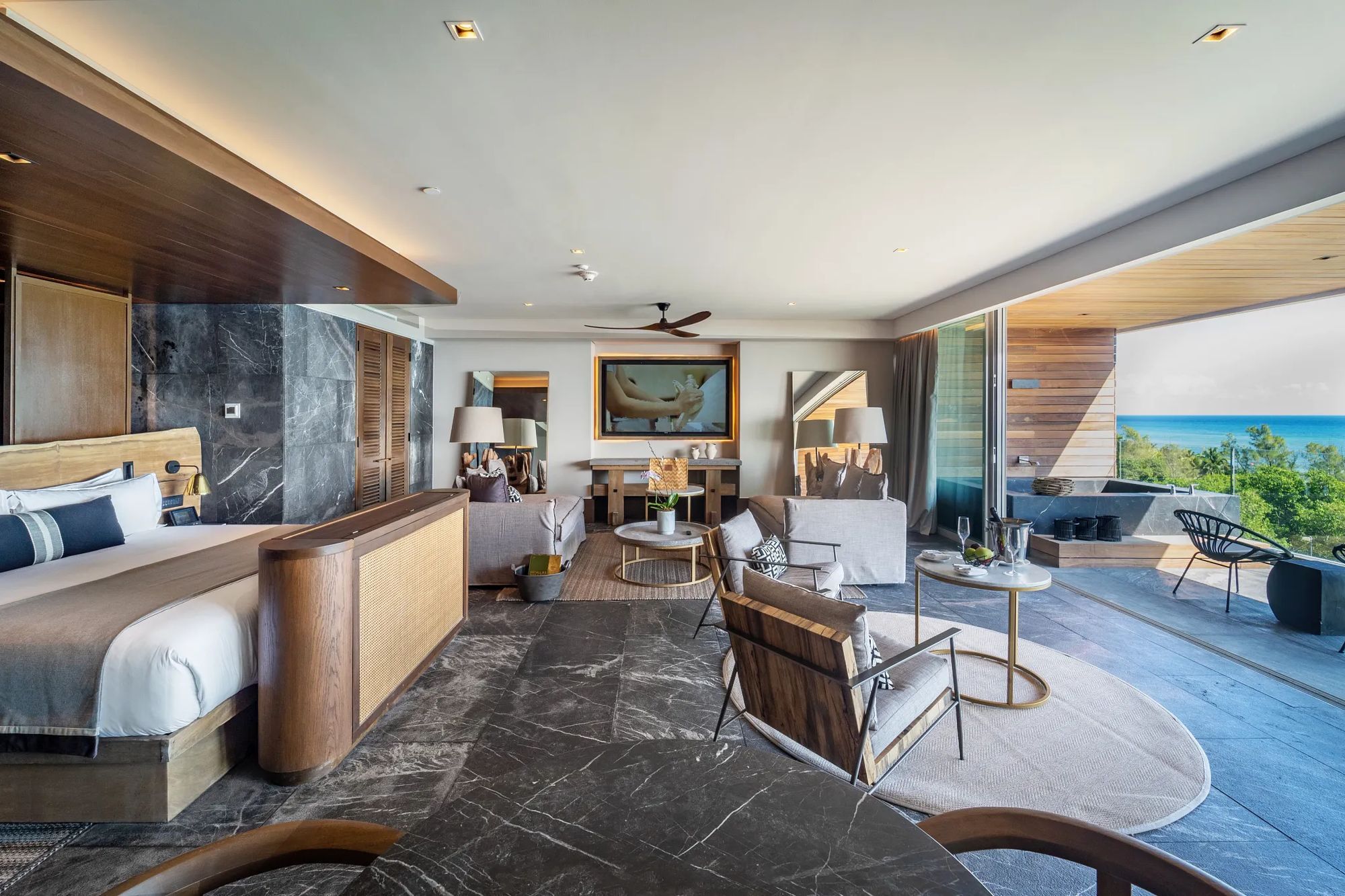 An oceanfront suite opening onto a terrace with loungers and turquoise water