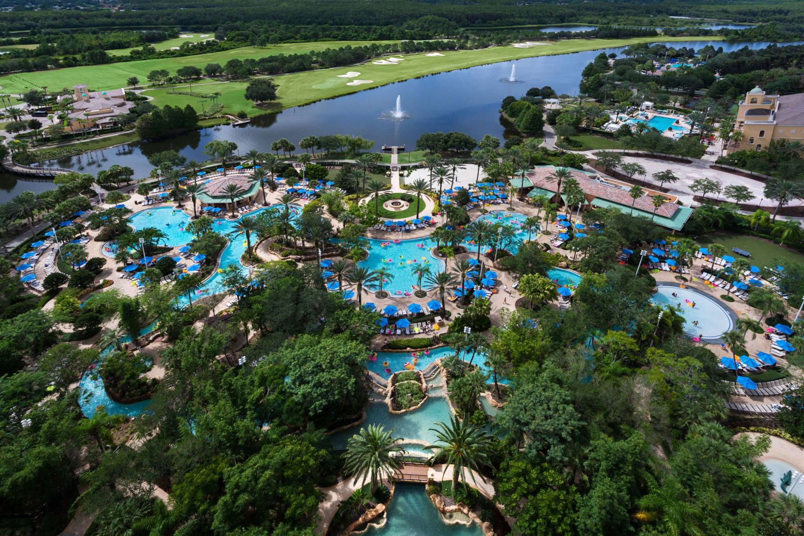 Aerial view of the resort's winding pools and lazy river among palms and lakes