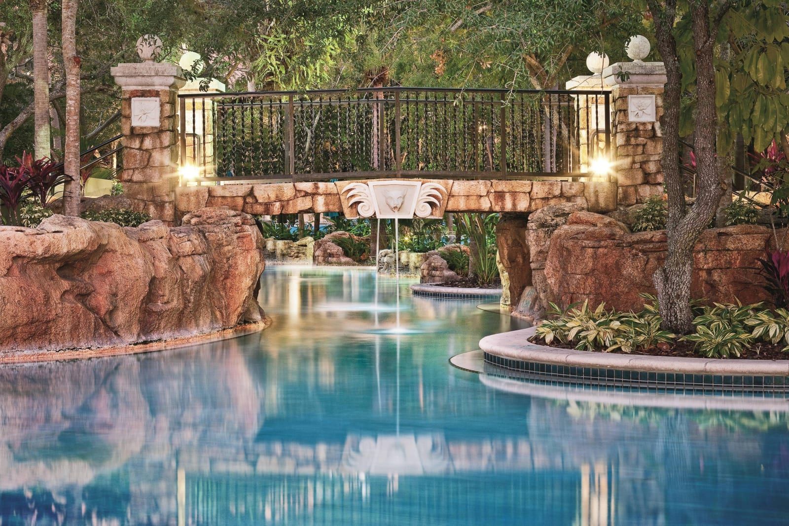 The lazy river curving under a stone footbridge