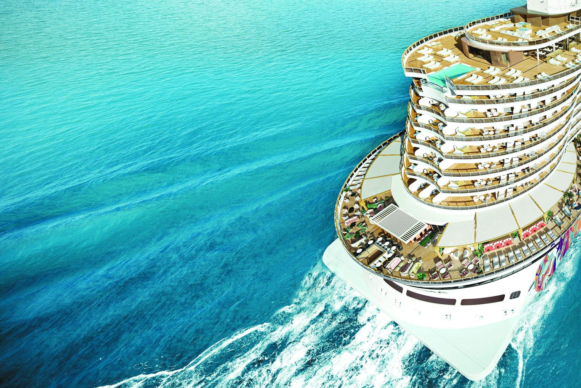 A Norwegian Cruise Line ship from above, cutting a wake through turquoise water