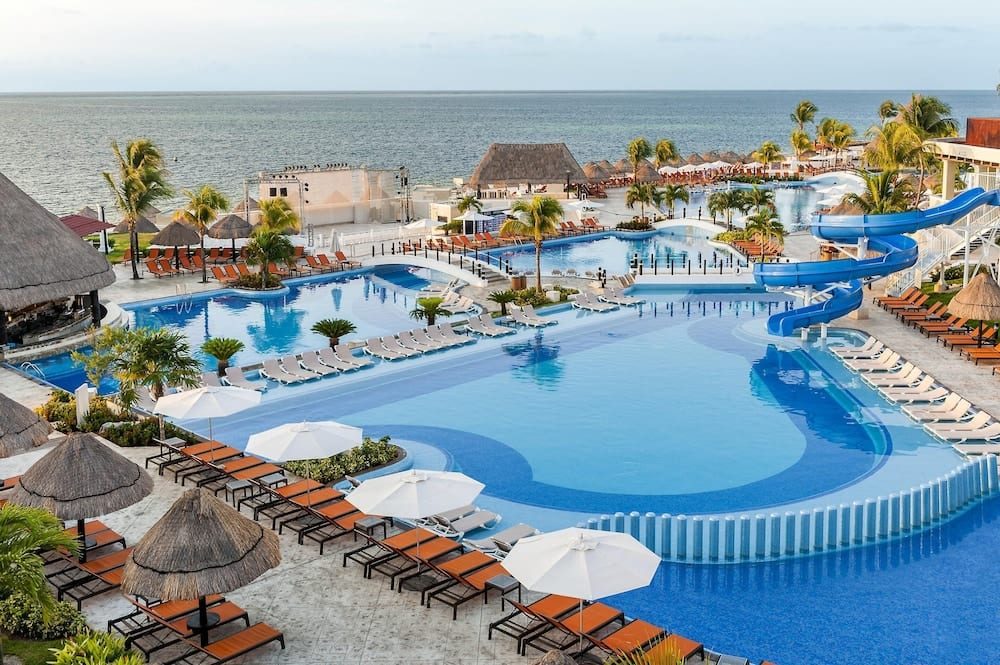 Moon Palace's pools and blue waterslides, with palapas and the Caribbean beyond