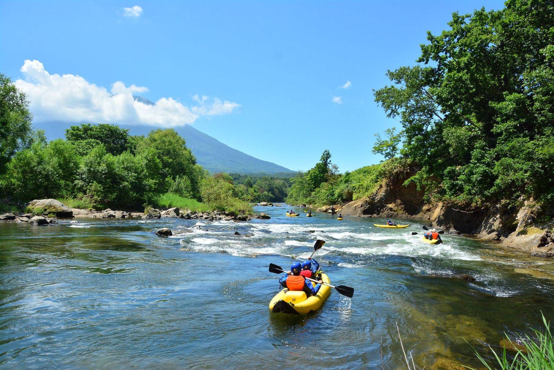 Rafting down a green river below Mt. Yotei in summer