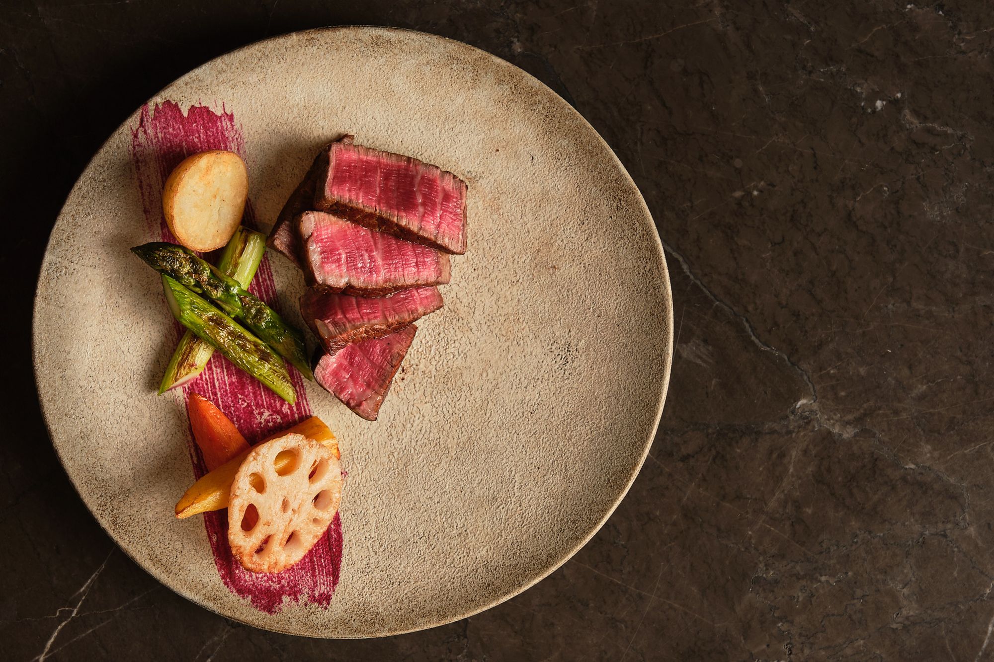 Sliced wagyu with grilled vegetables on a stone plate