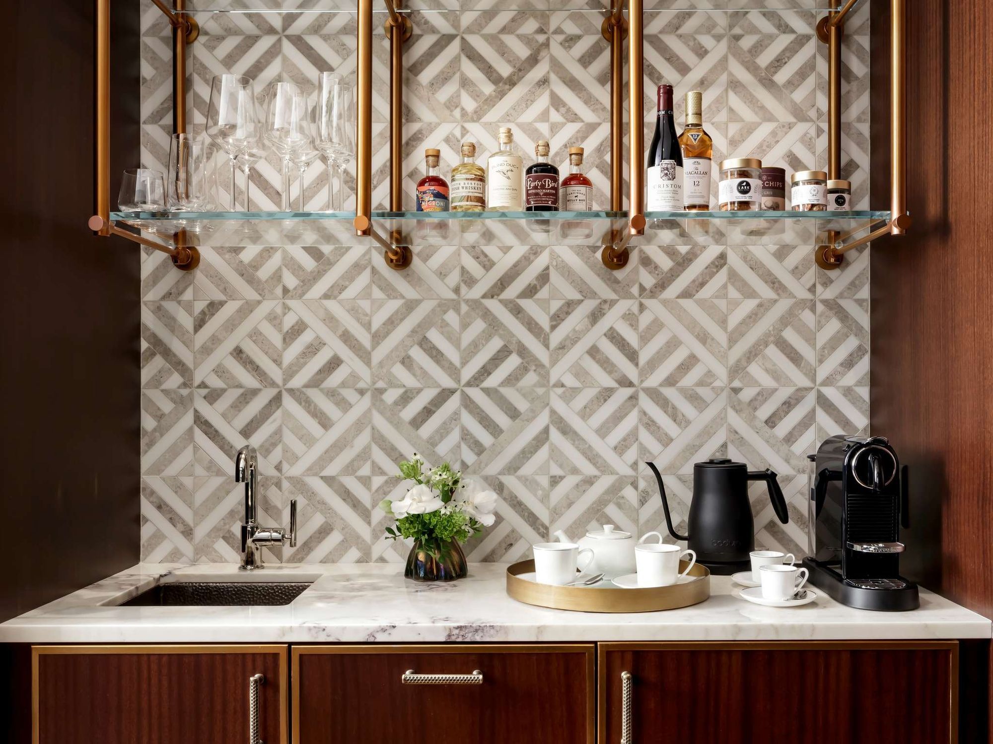 An in-room coffee bar with patterned tile and brass shelves