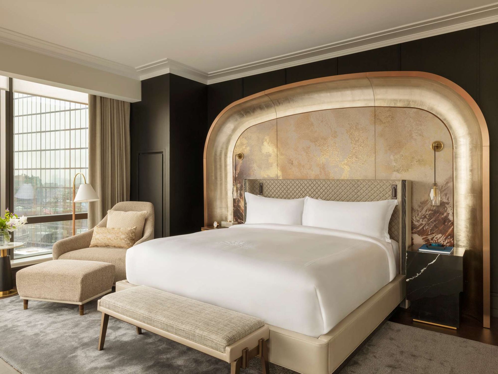A king room with an arched, gilded headboard