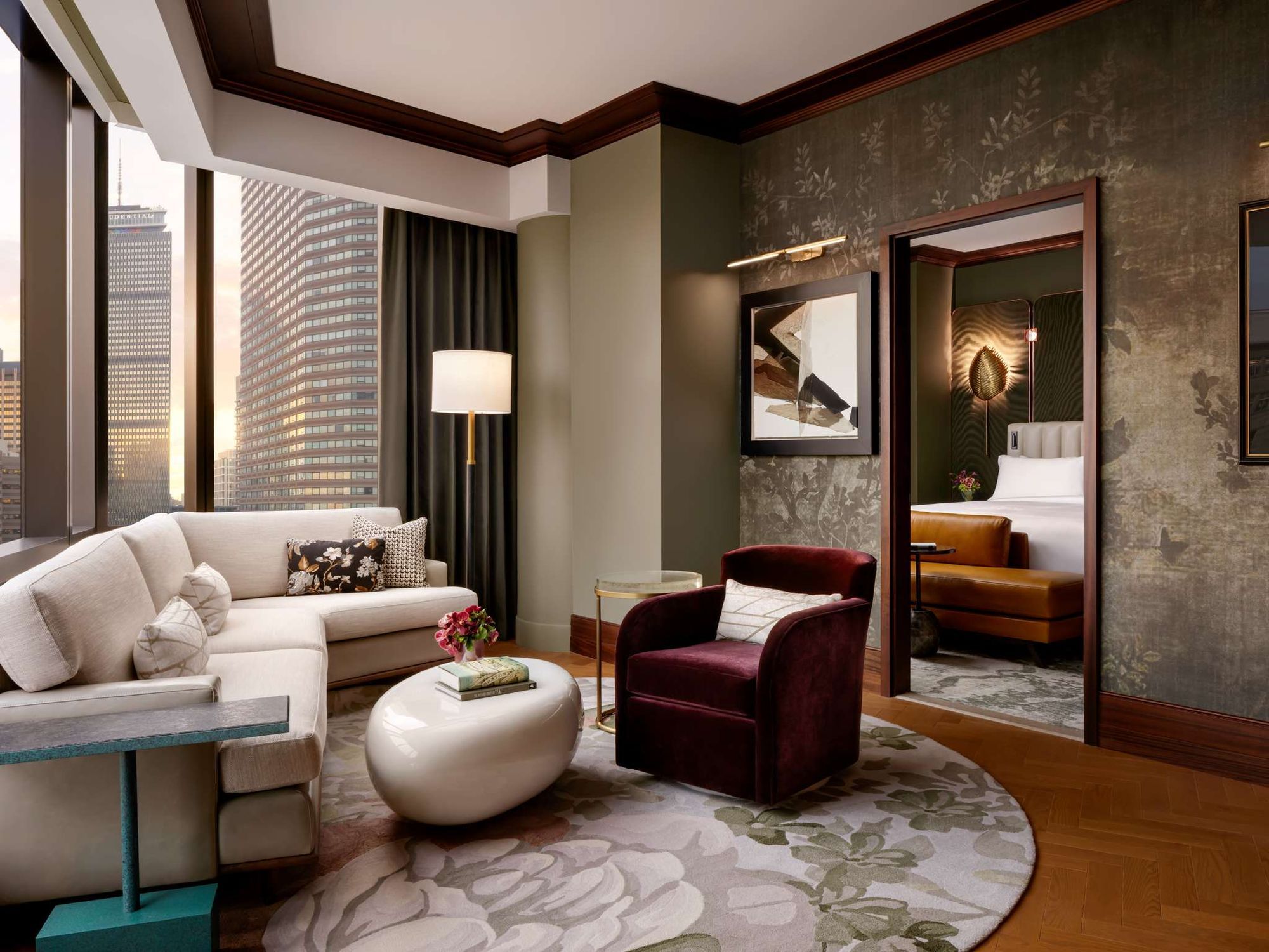 A suite sitting room with a curved sofa and a view of the city
