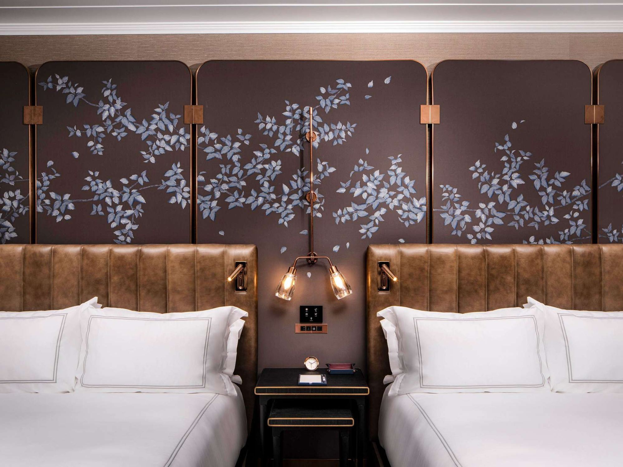 Two beds beneath a painted floral headboard wall