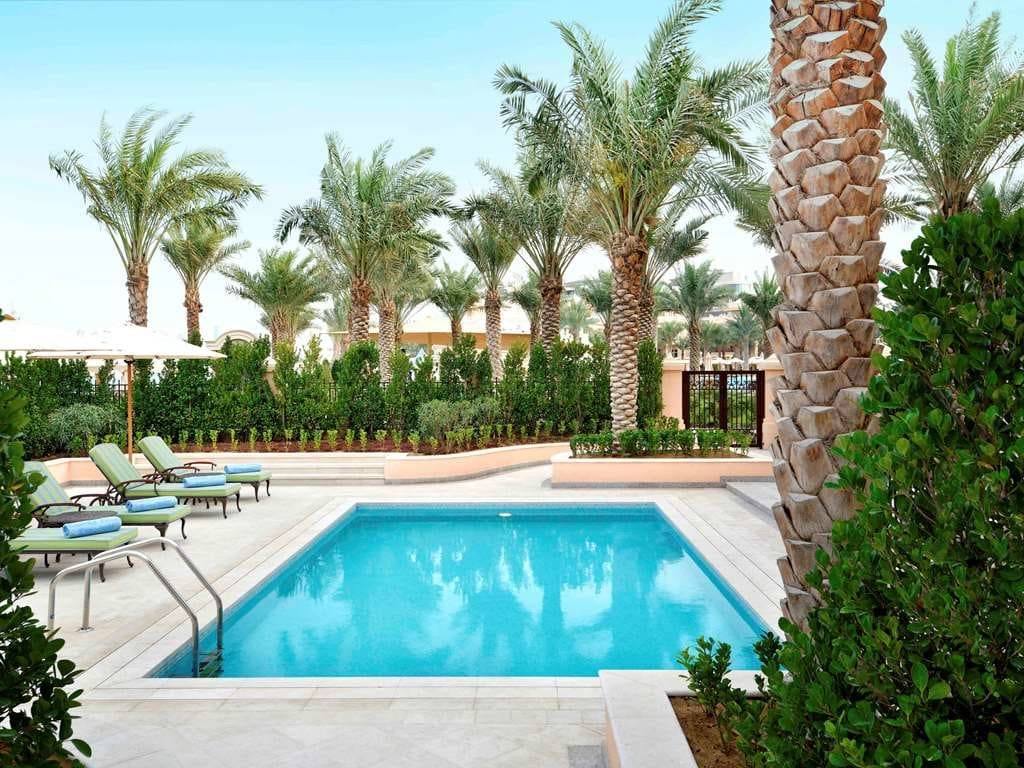 A quiet pool in a walled garden of palms and hedges