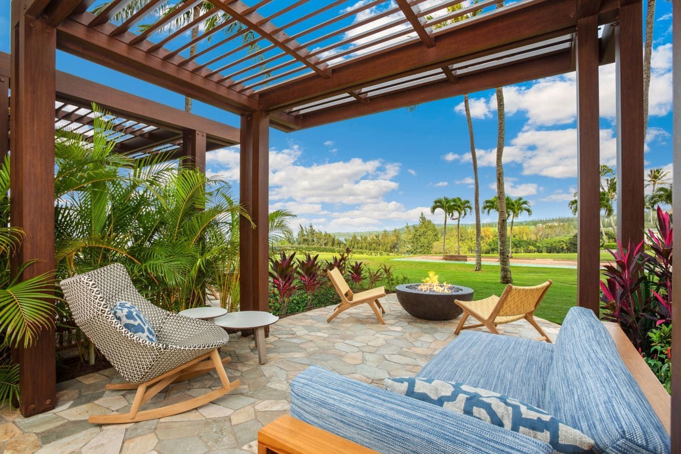 A shaded lanai with loungers and a fire bowl