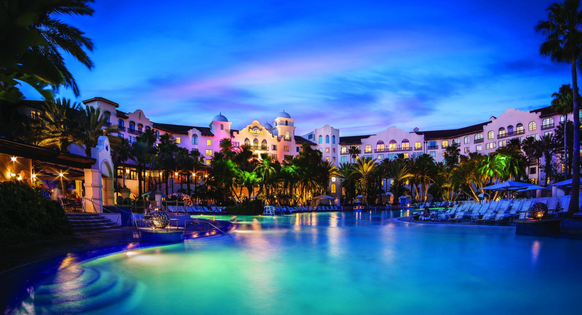 The pool at Hard Rock Hotel at dusk, lit blue beneath palms