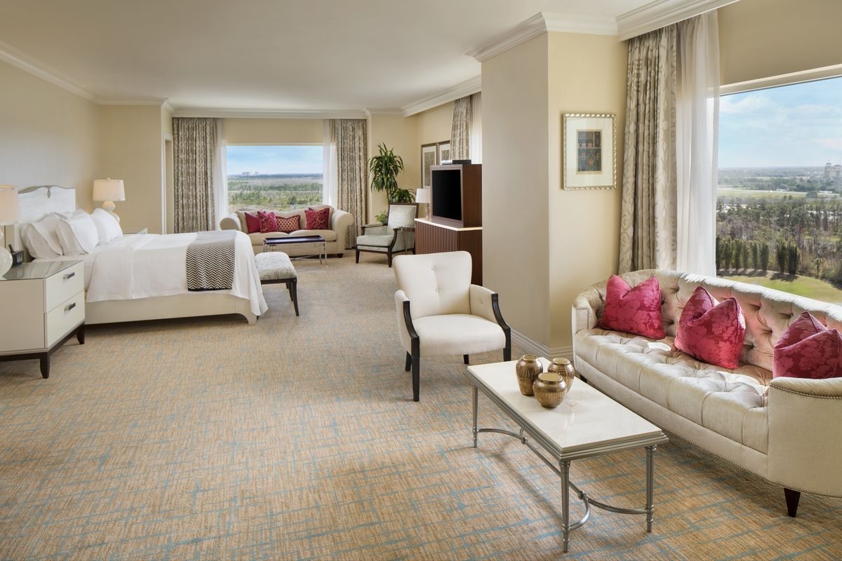 A suite bedroom with a sitting area and wide windows